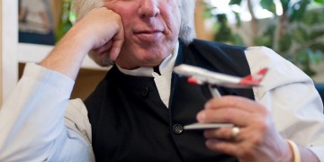 a man sitting in a chair holding a model airplane