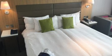 a bed with white sheets and green pillows