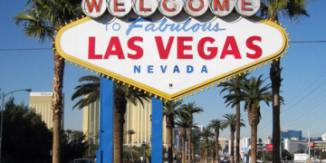 a sign with palm trees and buildings in the background with Welcome to Fabulous Las Vegas sign in the background