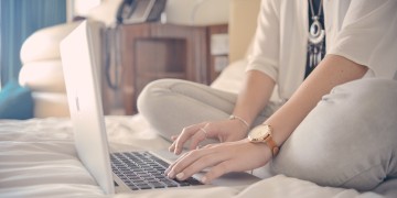 a woman sitting on a bed using a laptop