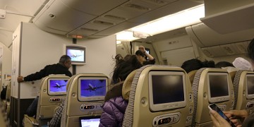 people sitting in an airplane with a laptop on the back