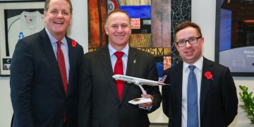 a group of men in suits holding a model airplane