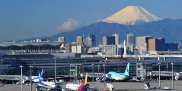 a group of airplanes on a runway with a mountain in the background