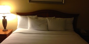 a bed with white sheets and pillows