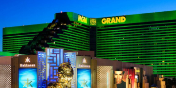 a large hotel with a large statue with MGM Grand Las Vegas in the background