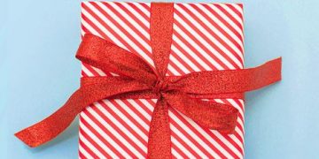 a gift wrapped in red and white striped paper with a bow