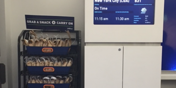 a display with a sign and a group of bags in a cart