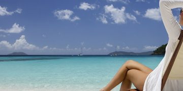 a woman lying on a chair in front of a body of water