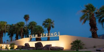 a building with palm trees and a sign