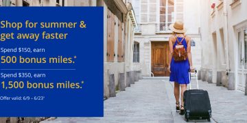 a woman in a blue dress and hat walking down a sidewalk with a suitcase