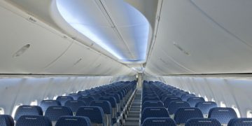 an airplane with blue seats with Milwaukee Art Museum in the background