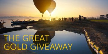 a group of people on a beach with hot air balloons