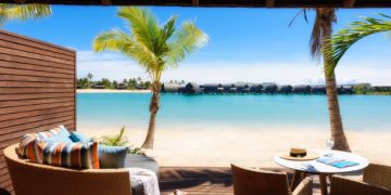 a deck with chairs and a table and a beach view