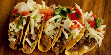 a group of tacos on a wood surface