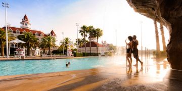 a group of people standing next to a pool