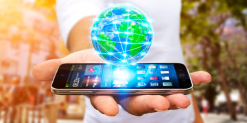 a hand holding a cell phone with a globe above it