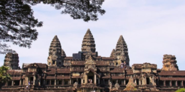 a large building with many towers with Angkor Wat in the background