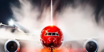 a red airplane with smoke coming out of it