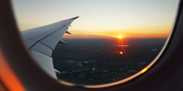 an airplane wing with the sun setting in the background