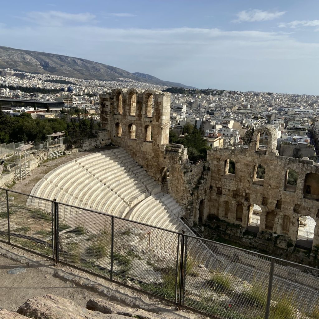 an old stone amphitheater with a city in the background