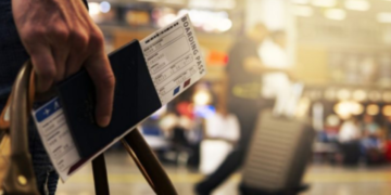 a hand holding a passport with boarding pass