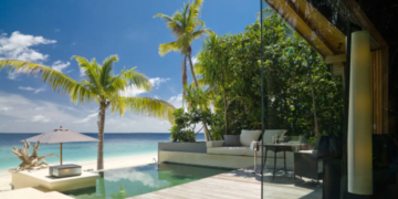 a pool with a couch and a table on the beach