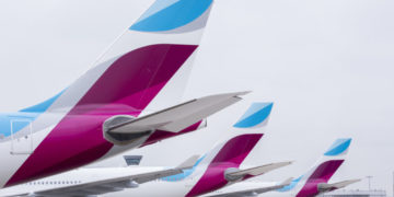 a row of airplanes with blue and purple tail fin