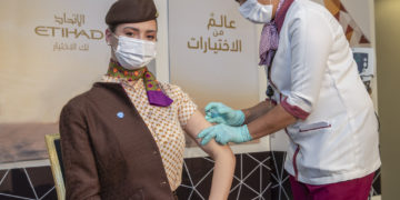 a woman wearing a mask and gloves getting an injection