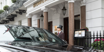 a man in a top hat standing in front of a hotel