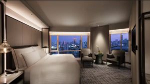 a room with a large bed and a table with chairs and a city view