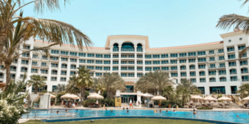 a large building with a pool and palm trees