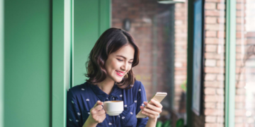 a woman holding a cup and a phone