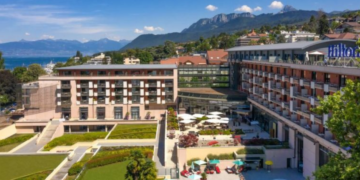 a hotel with a pool and mountains in the background