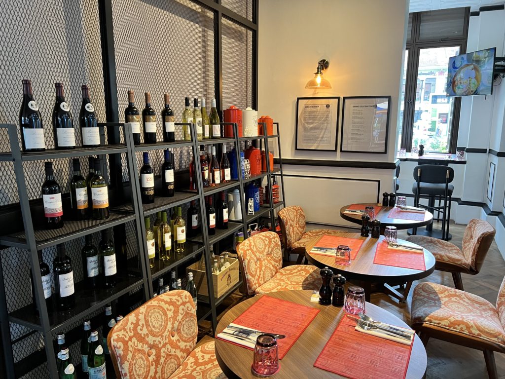 a room with tables and chairs and a shelf with wine bottles