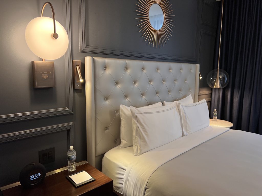 a bed with white pillows and a mirror above it