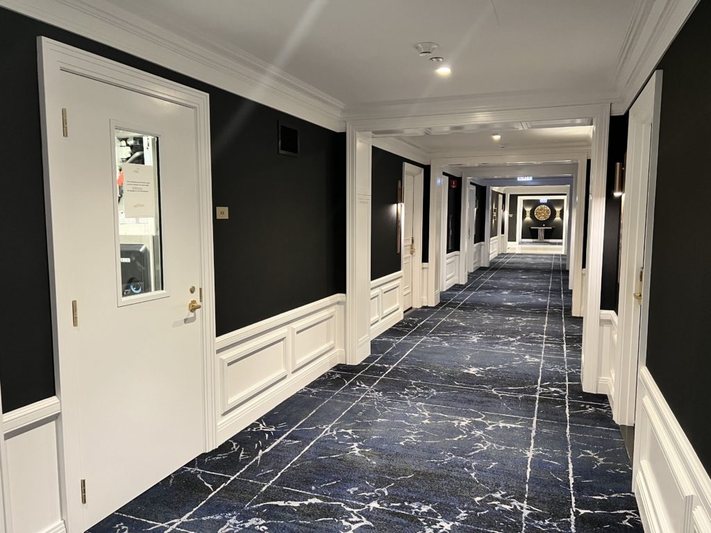 a hallway with white doors and blue carpet