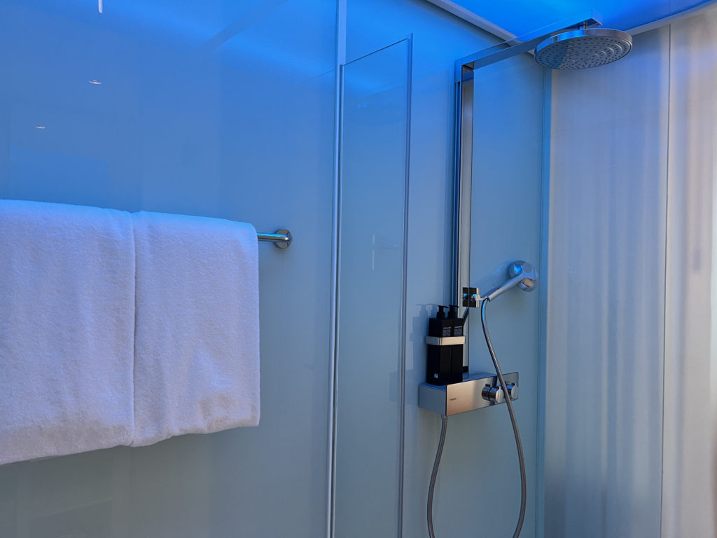 a shower with a shower head and a towel on a rack