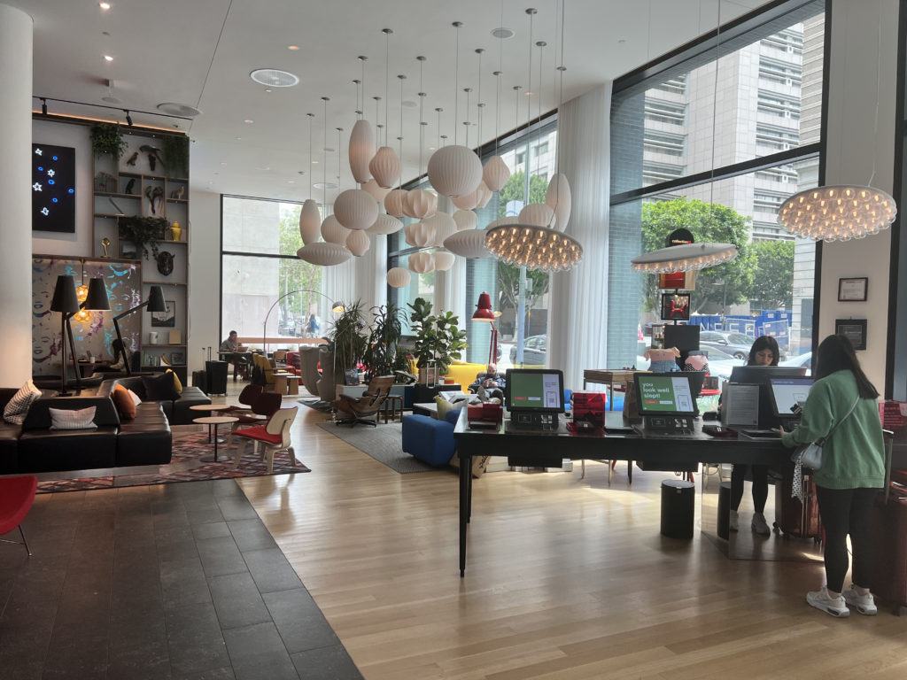 a room with a large window and a large table with a laptop and chairs