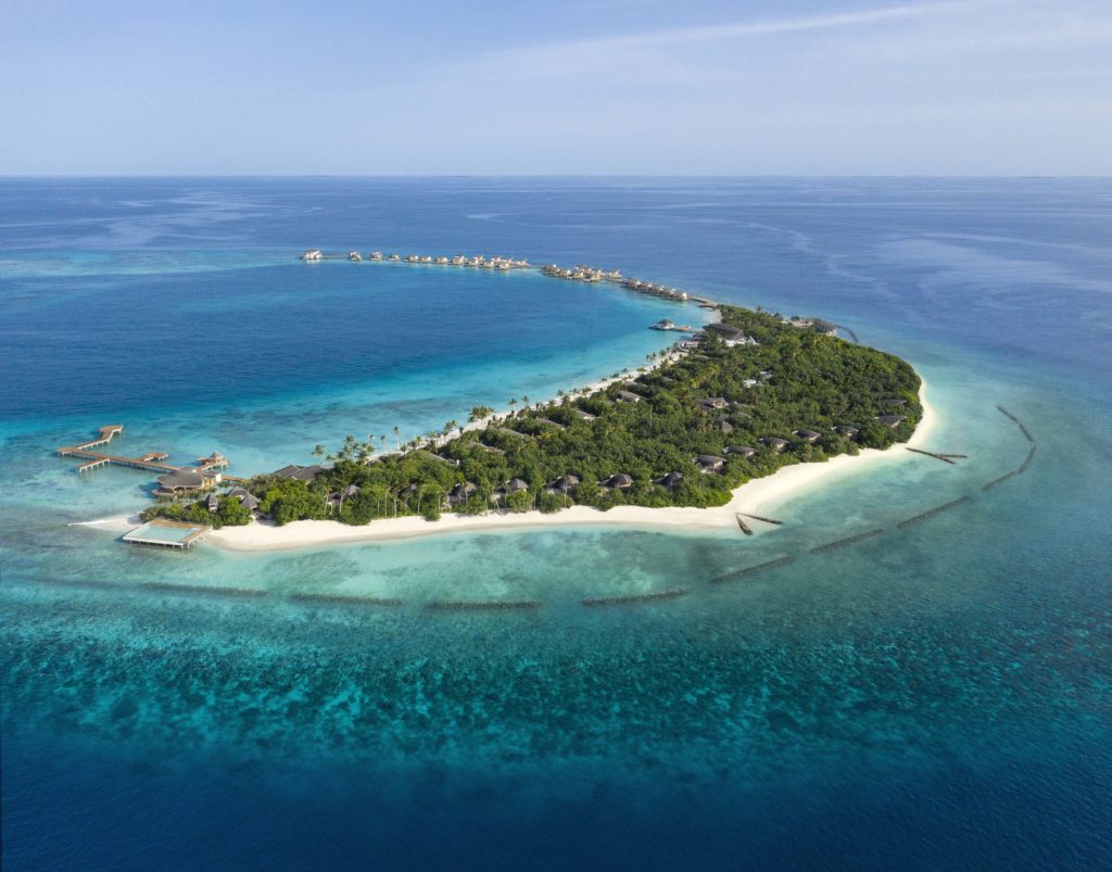 an island with trees and buildings in the middle of the ocean