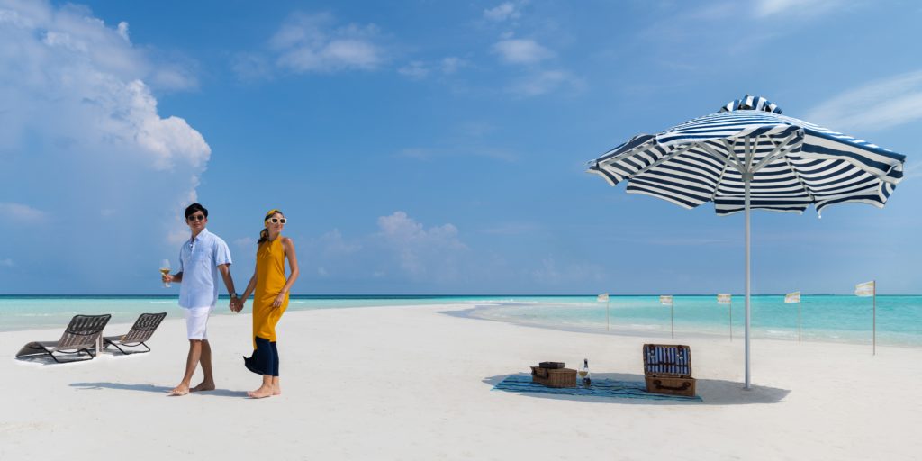 a man and woman holding hands on a beach